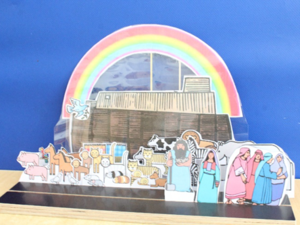 Die Schiene steht auf dem Tisch. Auf ihr ist die Geschichte Arche Noah aufgebaut. Dazu gehören Figuren der Arche, von Noah und seiner Familie, ein Regenbogen, die Arche und viele Tiere als Zweierpaare.